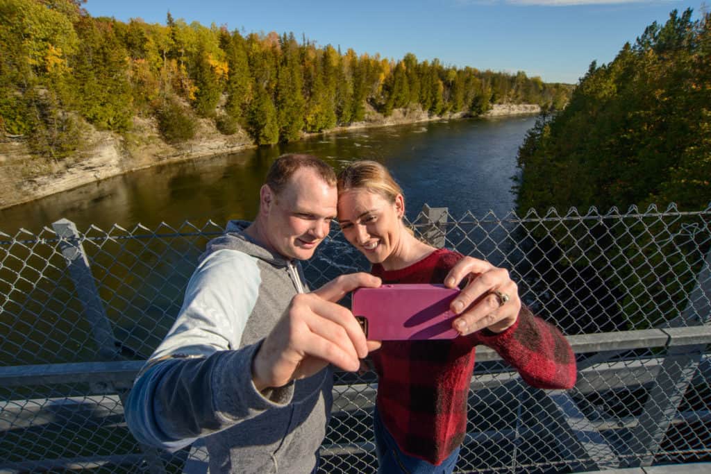 Couple taking photo from the Ranney Gorge Suspension Bridge in Campbelford Trent Hills Ontario