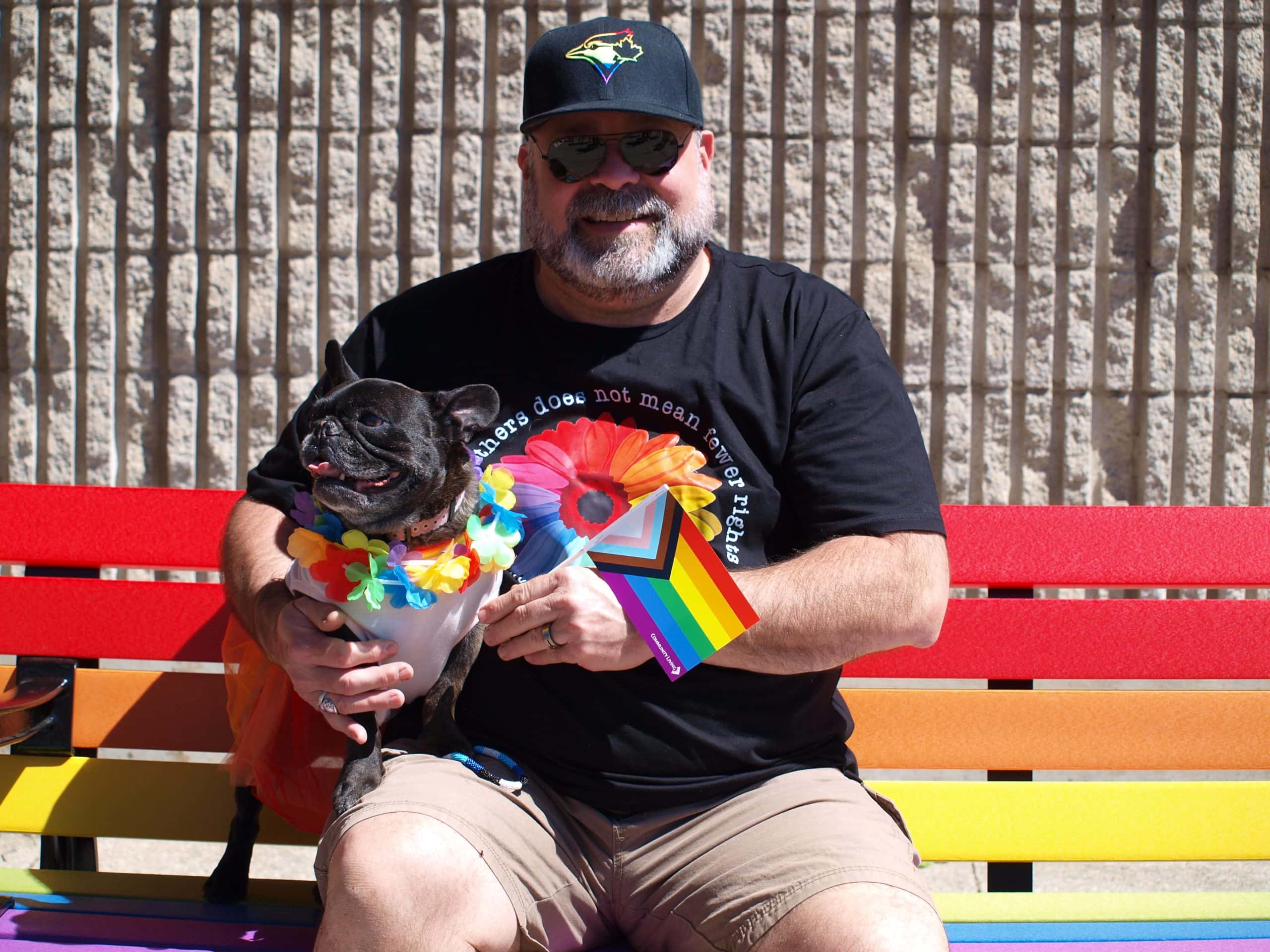 Man sitting on Pride bench with dog